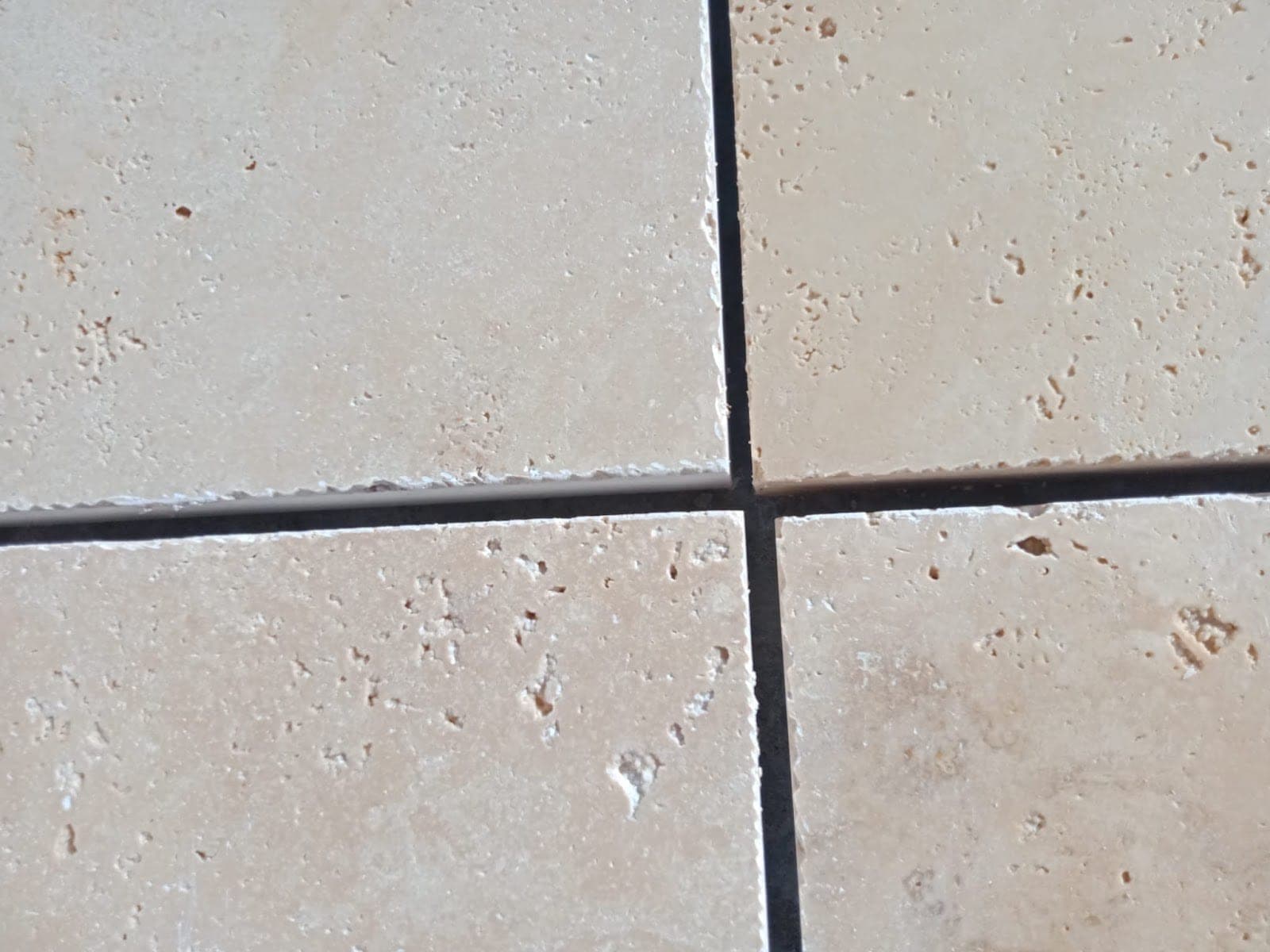 Frans verband Ivory, 3 cm: close-up van een getrommelde ivoorkleurige tegel met natuurlijke gaatjes