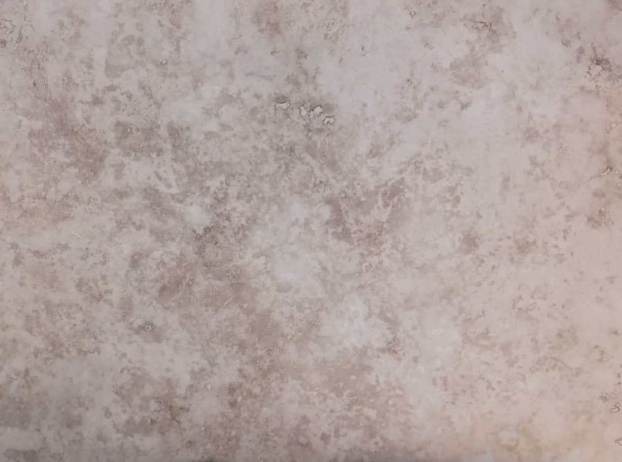 Ivory cross-cut: ivoor-grijze travertin met zacht gewolkt patroon, gezoet, close-up