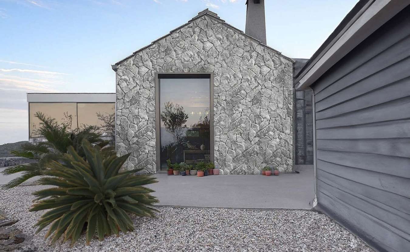 House with a facade of blue-grey polygonal wall stone and a driveway