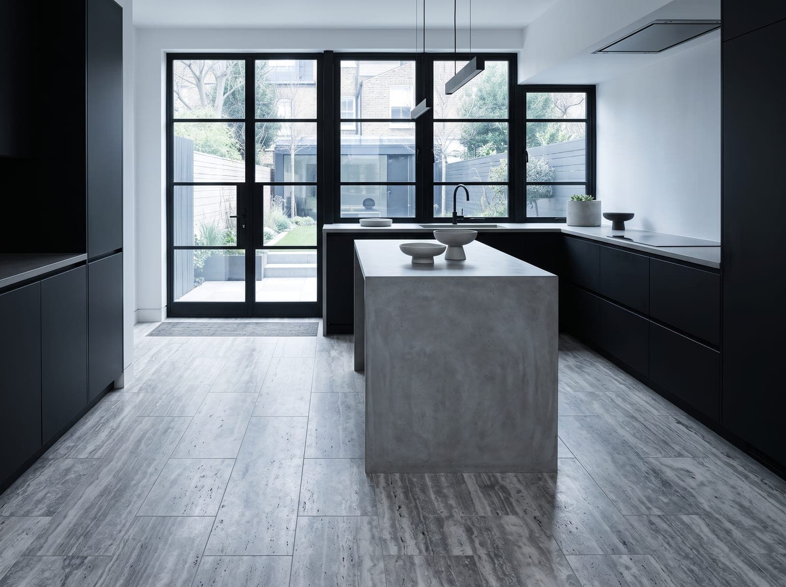 Moderne keuken met zilvergrijze vein-cut travertinvloer, matzwarte kasten en stalen kozijnen